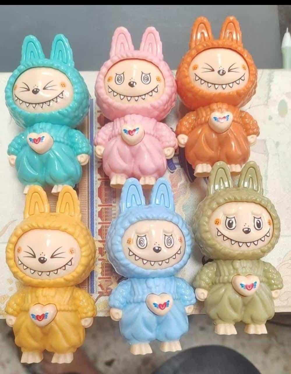 Set of colorful cartoon character figurines with bunny ears on a white surface.